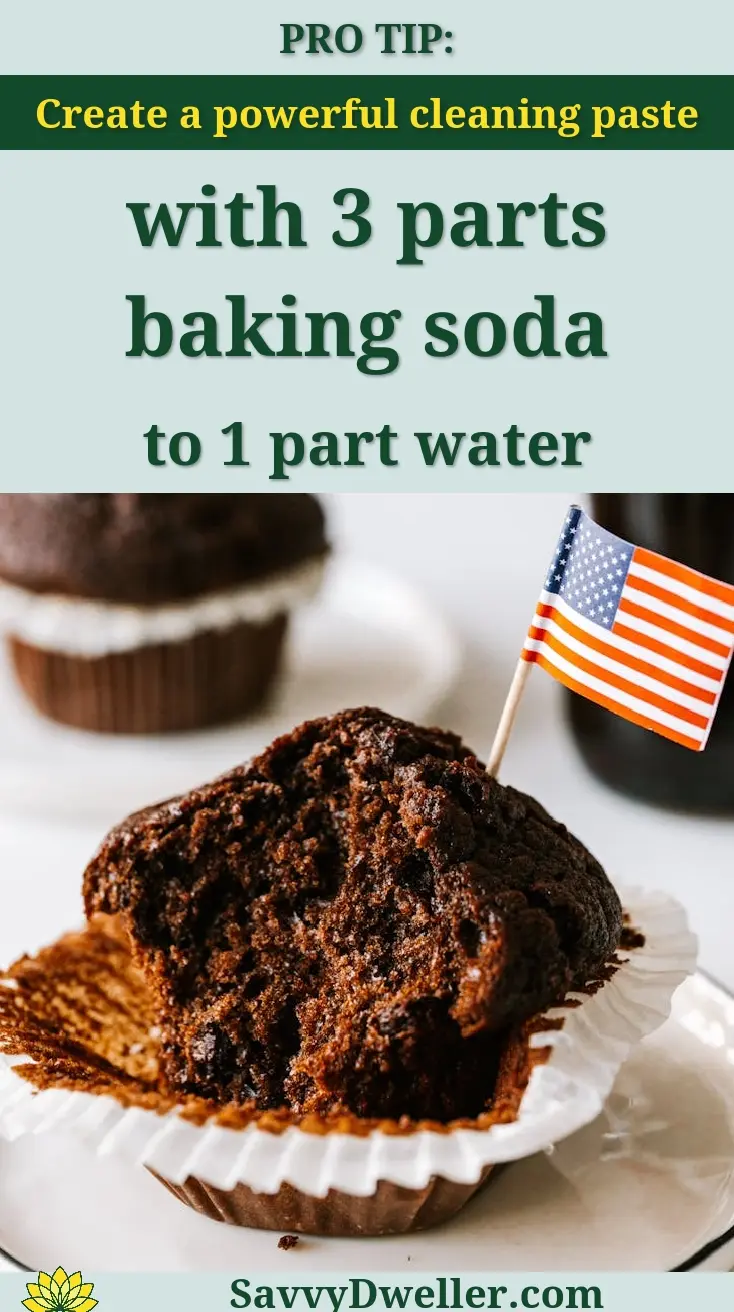Bitten chocolate cupcake decorated with miniature US flag and served on plate with bottle of cola and muffin on background