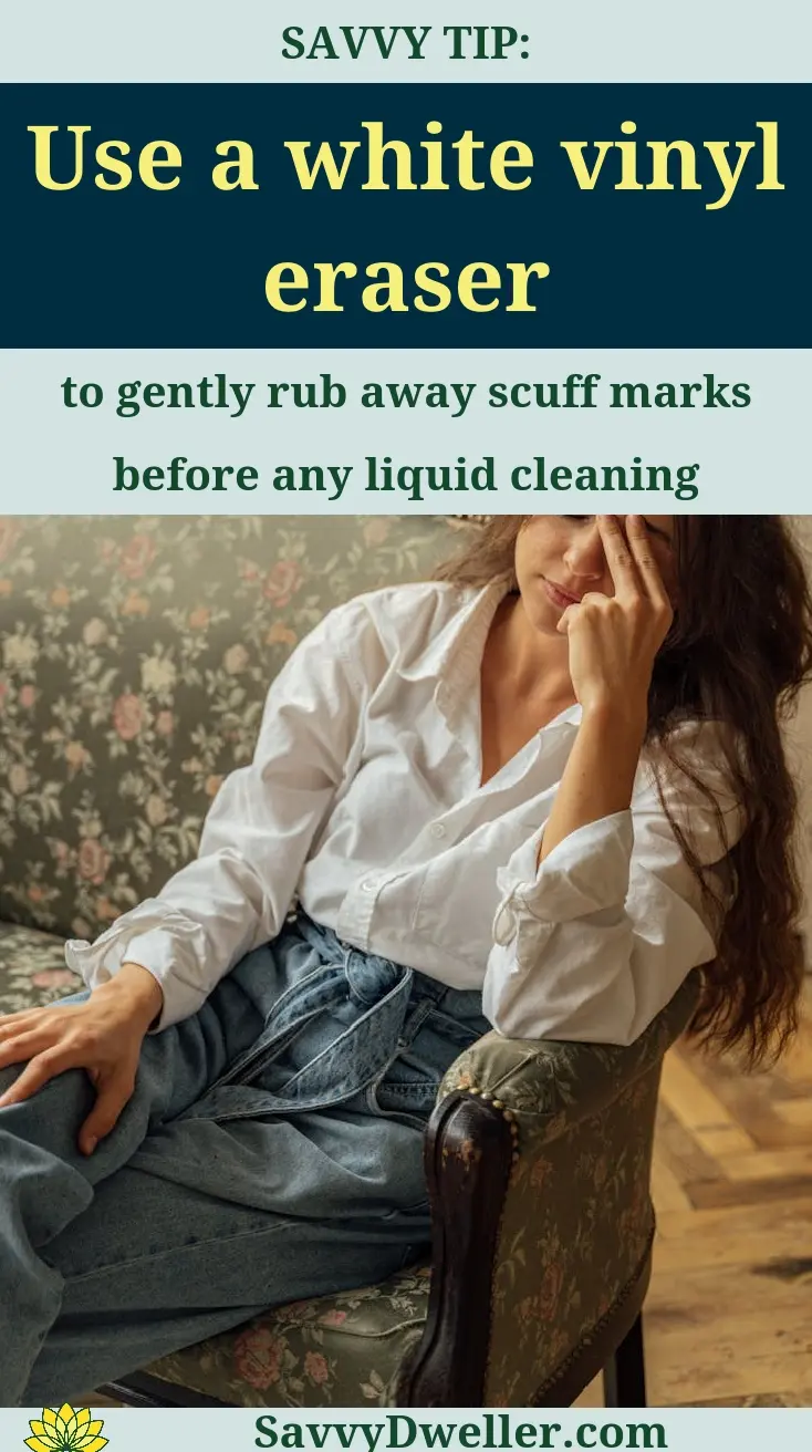 A woman demonstrating how to clean a microfiber couch using a white vinyl eraser.
