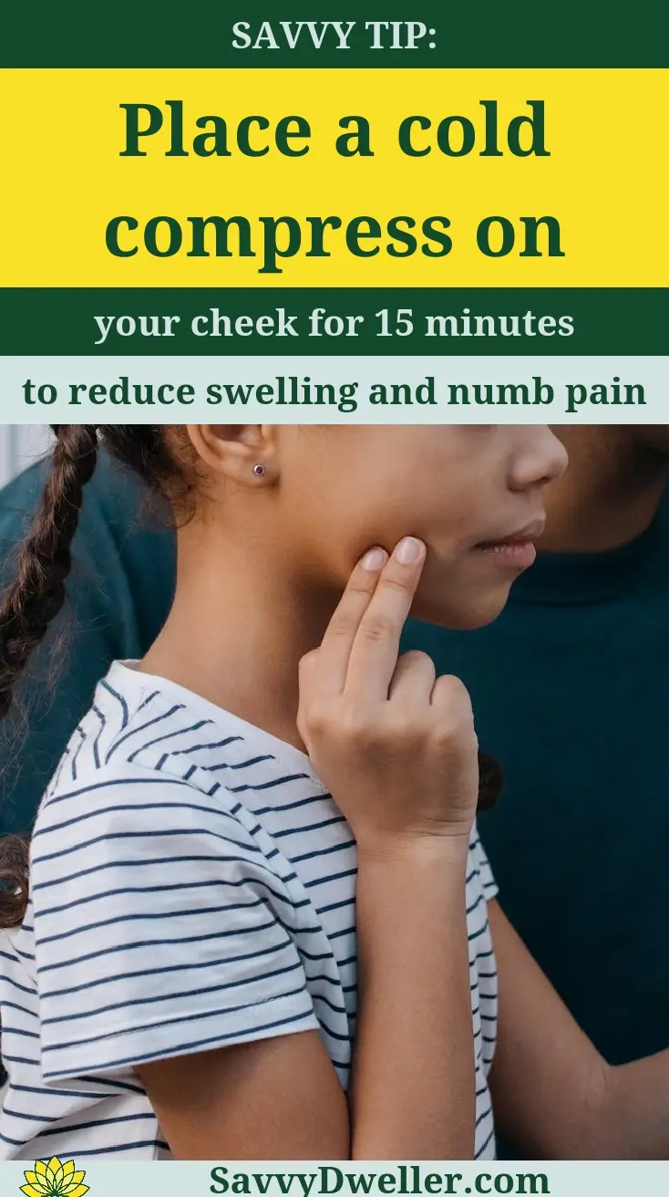 A person applying a cold compress to the cheek for toothache pain relief.