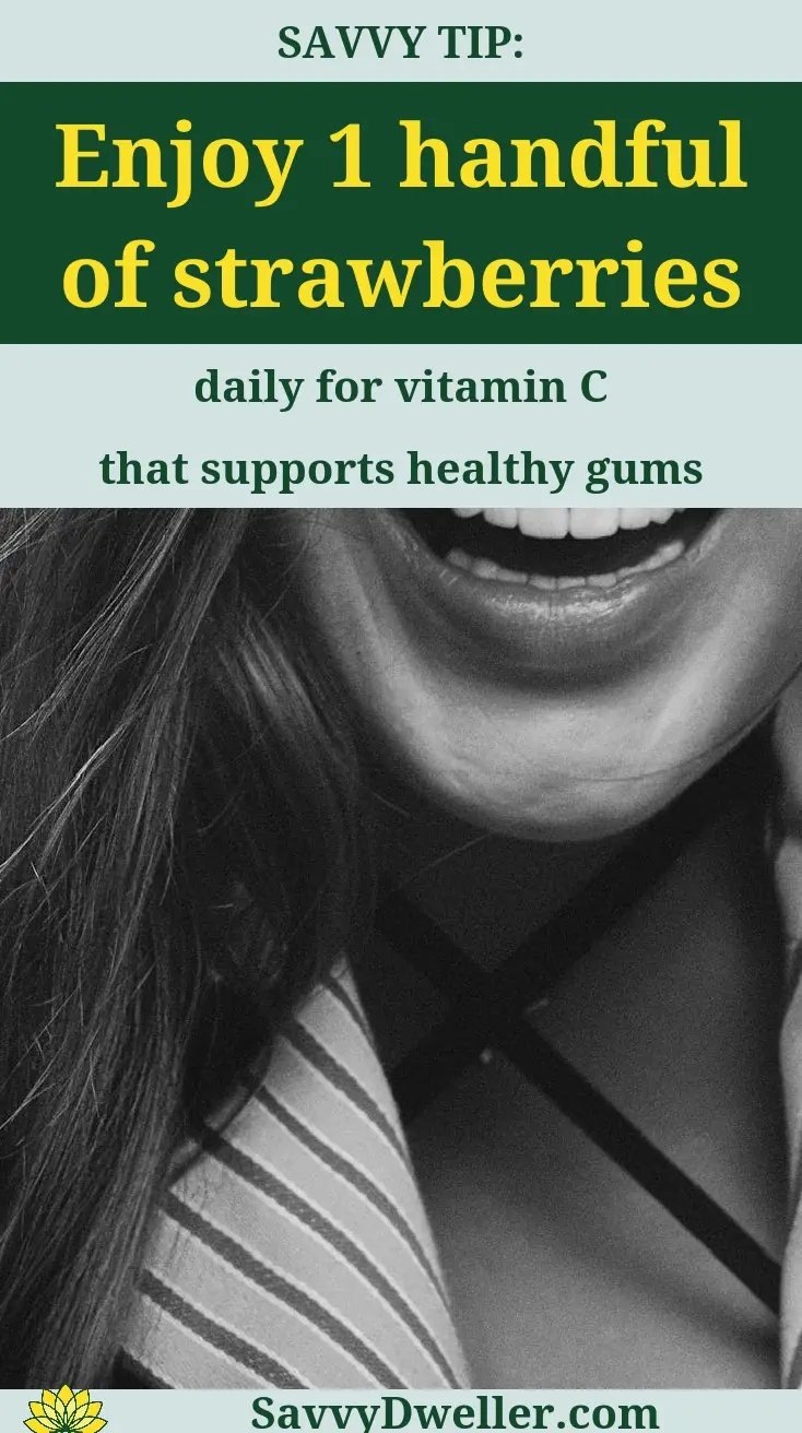 A woman smiling while holding strawberries, highlighting vitamin C benefits for healthy gums.