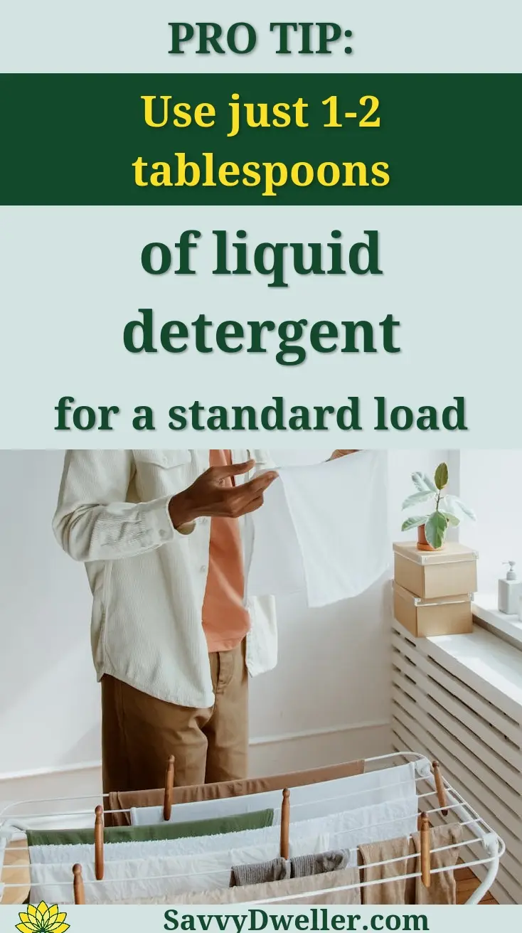 Adult man folding clothes in a bright home interior with laundry rack and plant nearby.