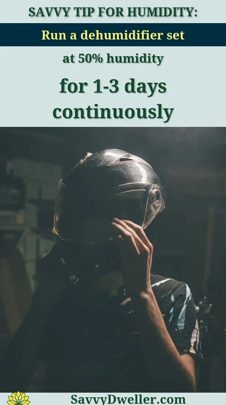 Dramatic low-light portrait showing a person adjusting a motorcycle helmet indoors.