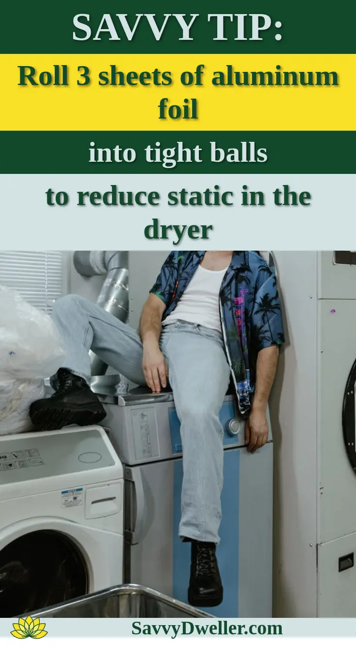 Casual man in blue shirt sitting on washing machine in industrial laundry setting.