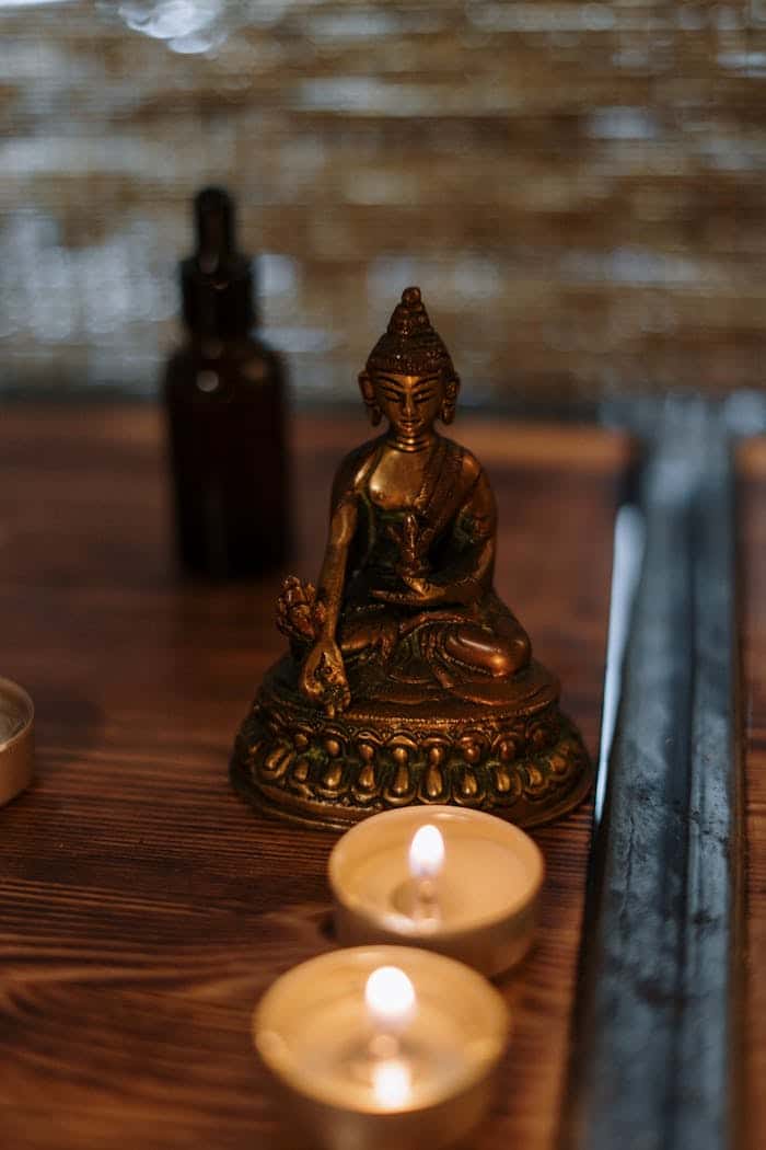 hero-about Buddha statue with candles creating a serene spa atmosphere, ideal for relaxation and mindfulness.