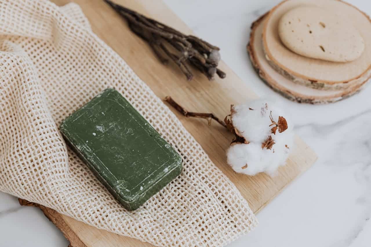 about-01 Natural green soap with cotton and loofah on wooden board promoting zero waste lifestyle.