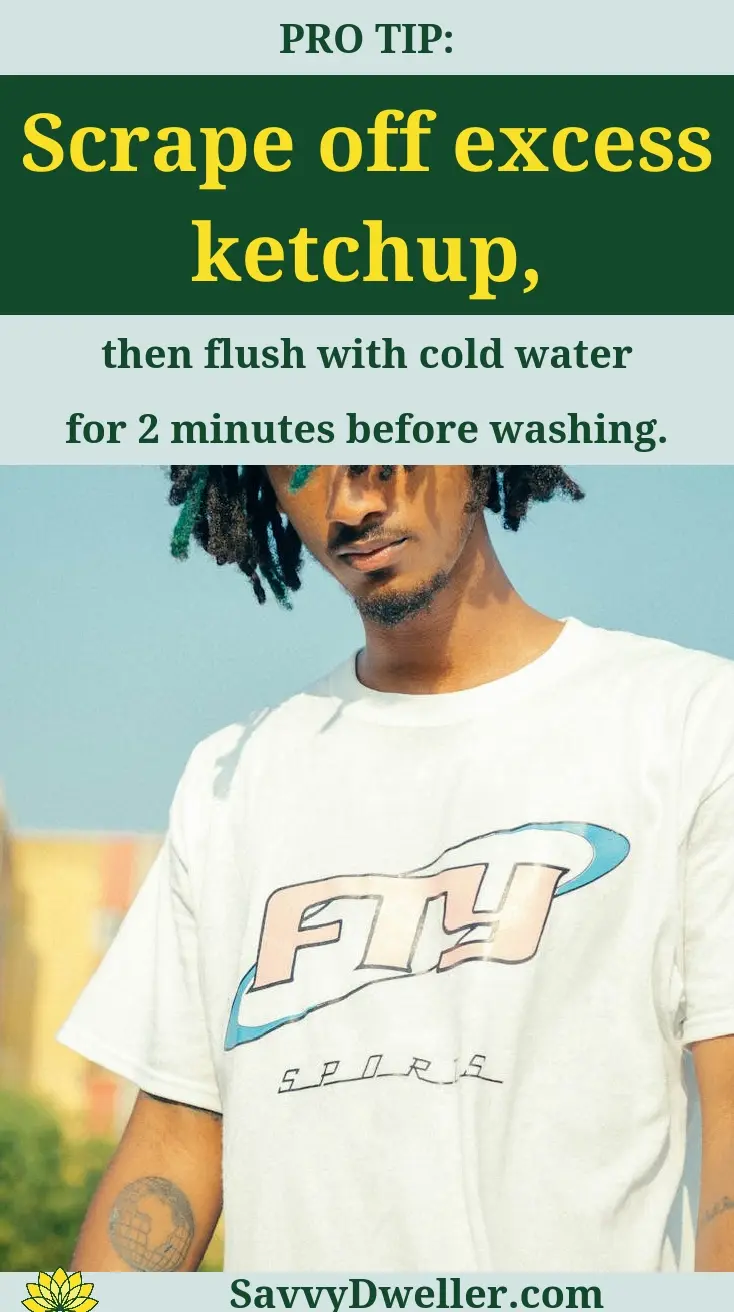 A person demonstrating how to scrape off excess ketchup from a white shirt to remove stains.