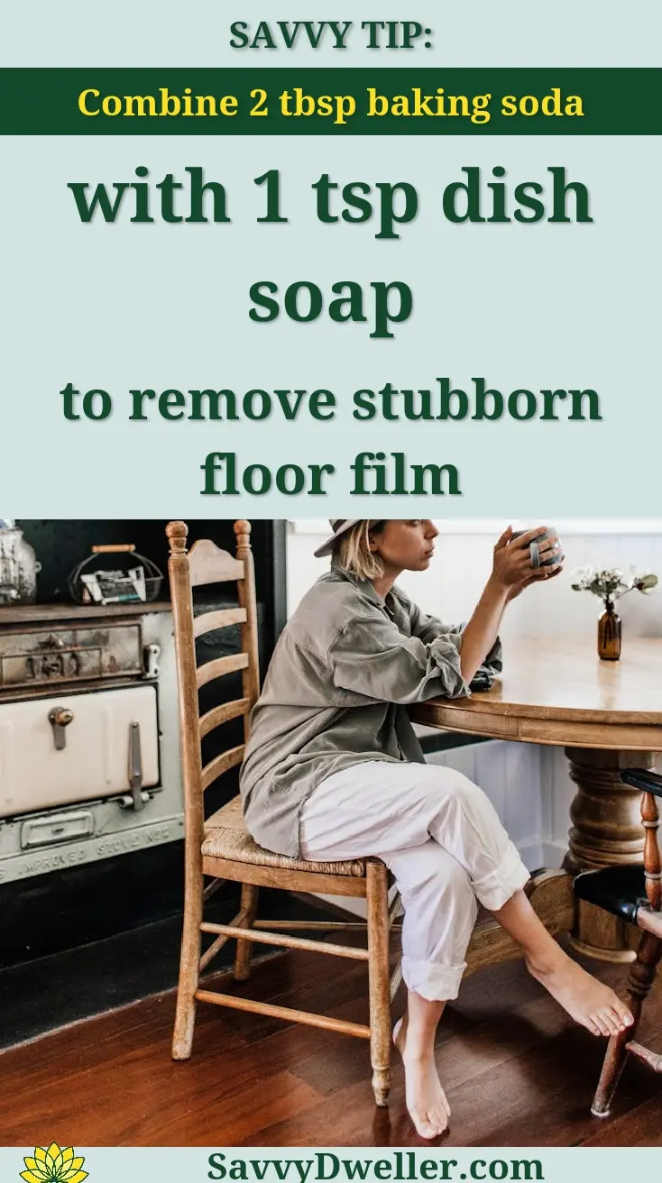 Side view of young stylish female in hat sitting at table in kitchen and drinking tea